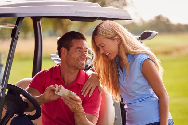 couple sitting in buggy playing round on golf together - golf course golf people sitting imagens e fotografias de stock