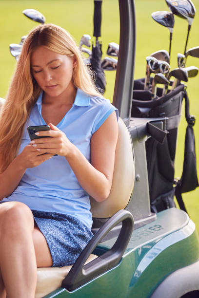 istock Woman Sitting In Golf Buggy And Using Mobile Phone 1356334348