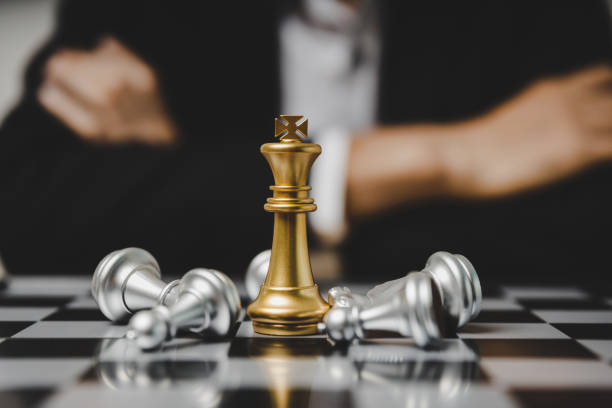 istock Checkmate. golden king with silver chess piece on chess board game competition on business man background, checkmate, chess battle, victory, success, team leader, teamwork, business strategy concept 1356334511