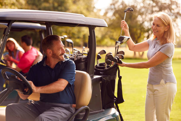 mature and mid adult couples in buggies playing round on golf together - golf four people young adult playing imagens e fotografias de stock