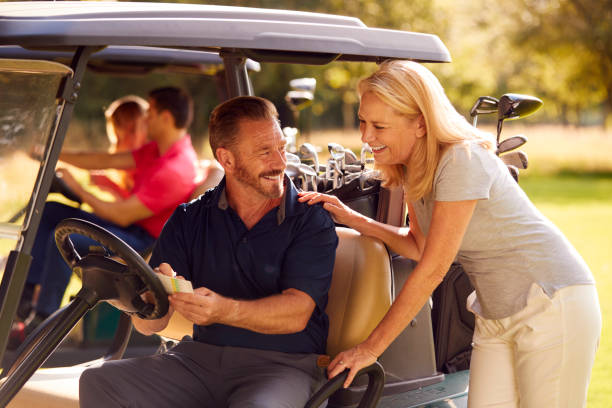 mature and mid adult couples in buggies playing round on golf together - golf four people young adult playing imagens e fotografias de stock