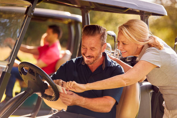 mature and mid adult couples in buggies playing round on golf together - golf four people young adult playing imagens e fotografias de stock