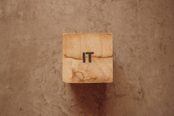 istock IT acronym text on wooden cube block on the old concrete table background 1356335359