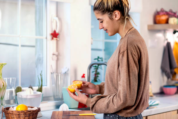 istock Young beautiful woman making a lemonade in domestic kitchen 1356335445