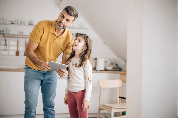 istock Little girl and her dad using a digital tablet to turn on home security system 1356338763
