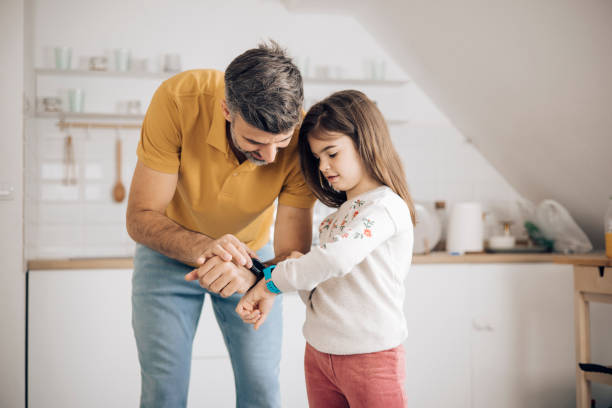 Dad teaching his little daughter how to use a smartwatch stock photo
