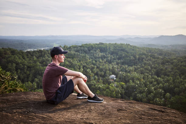 istock Pensive man resting at the edge of a rock 1356339791