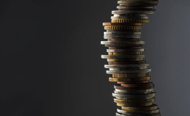 Stack of coins, studio shot. Large stack of international coins against a grey background. borrowing stock pictures, royalty-free photos & images
