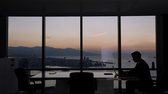 Businessman working at dusk in modern office.