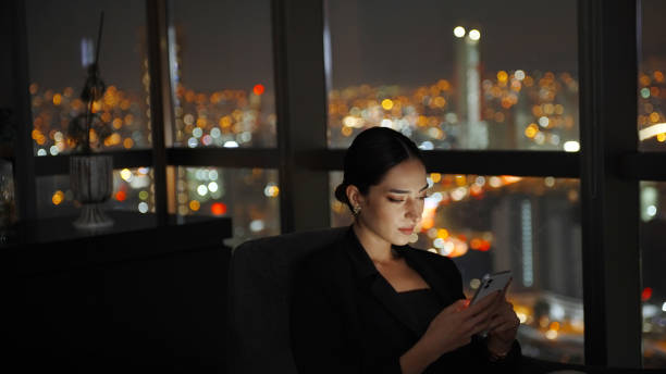 istock Businesswoman using phone at night 1356342219