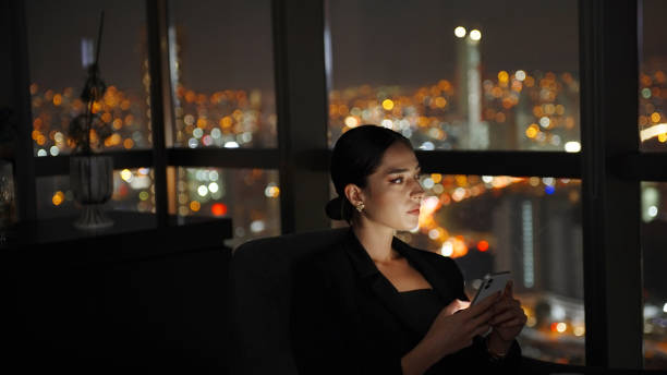istock Businesswoman using phone at night 1356342222