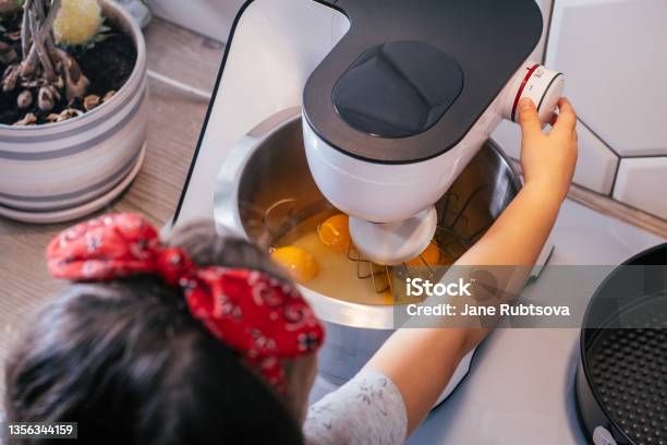 Little Darkhaired Girl 3 Years Old In Red Headband Bakes Apple Pie In Kitchen Child Turns On Planetary Mixer Top View Stock Photo - Download Image Now