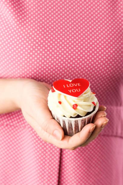 gâteau en forme de cœur dans les mains avec l’inscription i love you sur fond rose. cupcake en forme de cœur en gros plan - candy heart candy i love you heart shape photos et images de collection