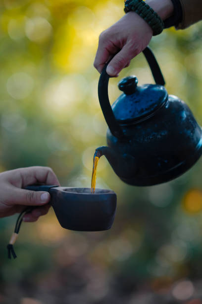 istock Bushcraft pours water from a bottle into a wood mug. 1356352646