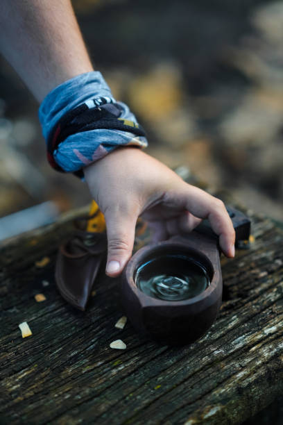 istock Bushcraft pours water from a bottle into a wood mug. 1356352650