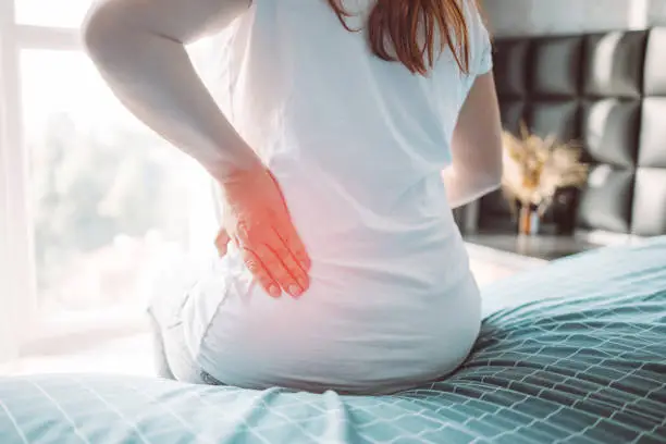 Cropped view of woman feel morning backpain after her wake up in bed. Healthcare concept