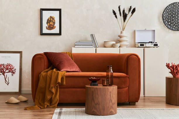 istock Creative composition of stylish living room interior with mock up poster frame, orange sofa, beige commode, coffee table and stylish personal accessories. Artistic space. Template. 1356352913
