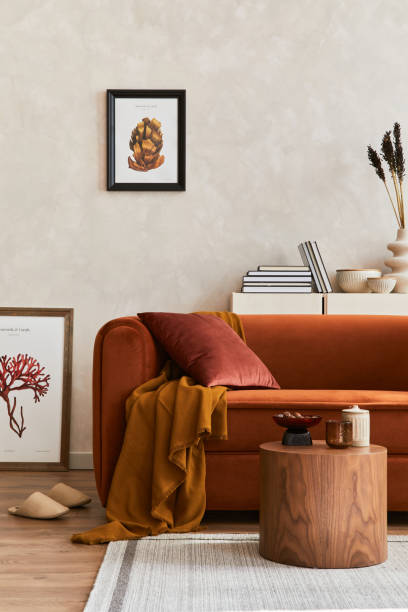 istock Creative composition of stylish living room interior with mock up poster frame, orange sofa, beige commode, coffee table and stylish personal accessories. Artistic space. Template. 1356352914