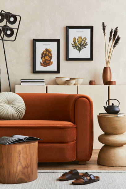 istock Creative composition of stylish living room interior with mock up poster frame, orange sofa, beige commode, coffee table and stylish personal accessories. Artistic space. Template. 1356352942