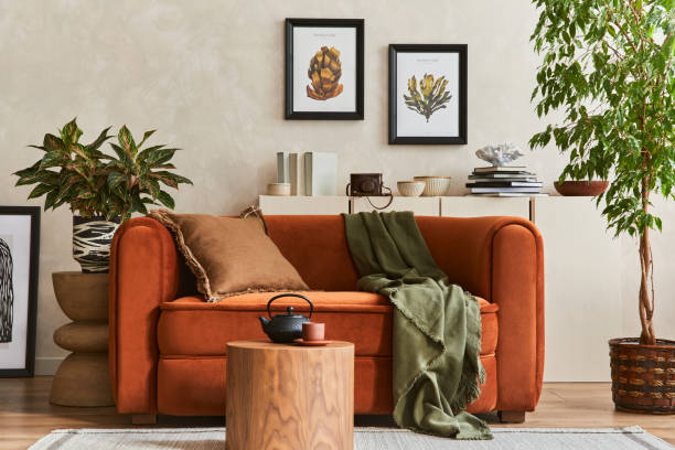 istock Creative composition of stylish living room interior with mock up poster frame, orange sofa, beige commode, coffee table and stylish personal accessories. Artistic space. Template. 1356352971