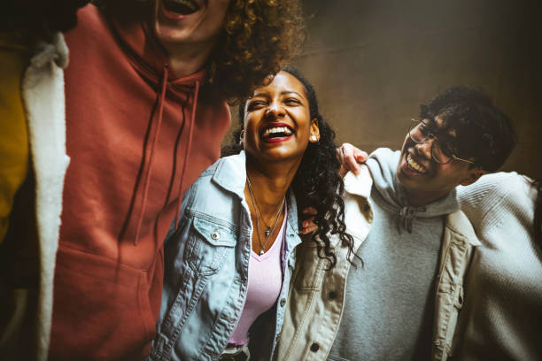 jóvenes felices riendo juntos - grupo de amigos multirraciales divirtiéndose en la calle de la ciudad - estudiantes de raza mixta pasando el rato juntos - amistad, comunidad, juventud, concepto universitario - fiesta callejera fotografías e imágenes de stock