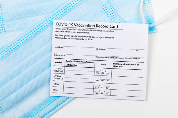 istock Coronavirus vaccination record card. Protective mask divided into two parts. Concept of defeating Covid-19 1356356366