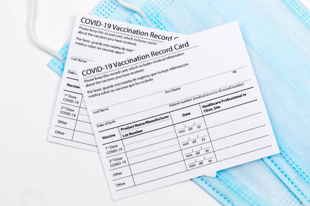 istock Coronavirus vaccination record card. Protective mask divided into two parts. Concept of defeating Covid-19 1356356513