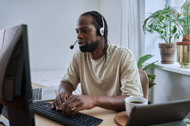 istock Multiracial man wearing headphones is browsing at his computer 1356356609
