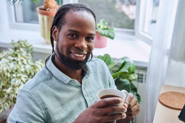 istock Handsome multiracial man holding cup with hot coffee and looking at the camera 1356357252