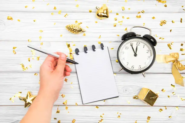 Festivedecorations and notebook with wish list and alarm  on white rustic table, flat lay style. Planning concept.