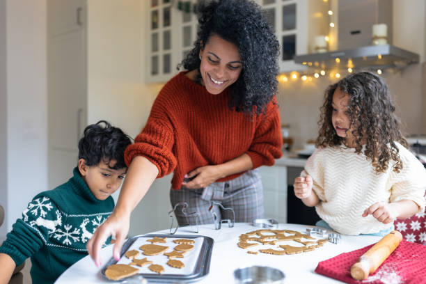 sœur et frère faisant des biscuits au pain d’épices de noël avec une mère - christmas december holiday holidays and celebrations photos et images de collection