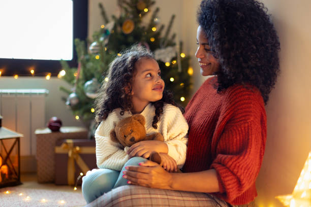 istock Daughter and mother  sitting by the Christmas tree 1356361943