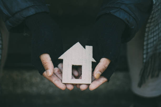 Poor tired depressed hungry homeless man holding a cardboard house. nostalgia and hope concept. Poor tired depressed hungry homeless man holding a cardboard house. nostalgia and hope concept. homelessness photos stock pictures, royalty-free photos & images