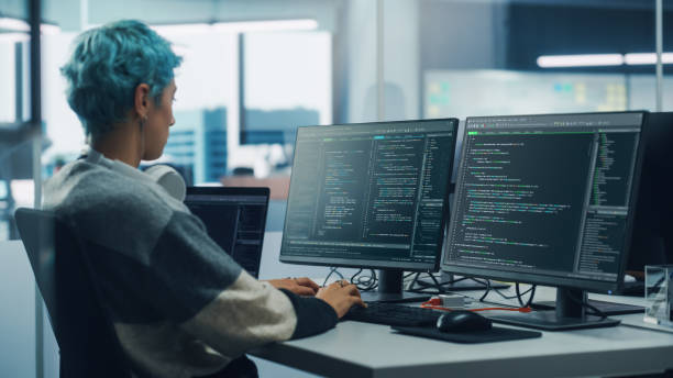 In Diverse Office: Female Programmer is Working on Desktop Computer, Screen Shows Coding Language User Interface. Digital Entrepreneur Creating Modern Software, e-Commerce App Design. Over Shoulder en diverse office: female programmer está trabajando en una computadora de escritorio, la pantalla muestra la interfaz de usuario del lenguaje de codificación. emprendedor digital creando software moderno, diseño de aplicaciones de comercio electrónico