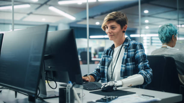 diverse body positive office: portrait d’une femme handicapée motivée utilisant un bras prothétique pour travailler sur ordinateur. professionnel avec une main bionique myoélectrique contrôlée par le corps contrôlée par la pensée avancée - prosthetic equipment photos et images de collection