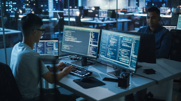 night office: young japanese man in working on desktop computer. diverse multi-ethnic team of programmers typing code, creating modern software, e-commerce app design, e-business programming. - computer programmer designer computer computer language imagens e fotografias de stock