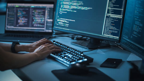 istock Close-up Focus on Person's Hands Typing on the Desktop Computer Illuminated Keyboard. Screens Show Coding Language User Interface. Software Engineer Create Innovative Commerce App. Program Development 1356364303