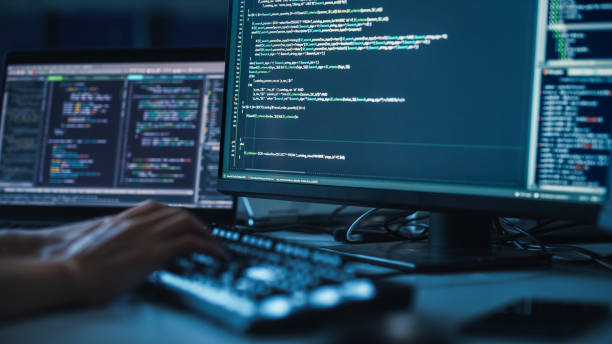istock Close-up Focus on Person's Hands Typing on the Desktop Computer Illuminated Keyboard. Screens Show Coding Language User Interface. Software Engineer Create Innovative Commerce App. Program Development 1356364310