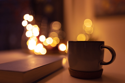 Tea, book and defocused Christmas lights