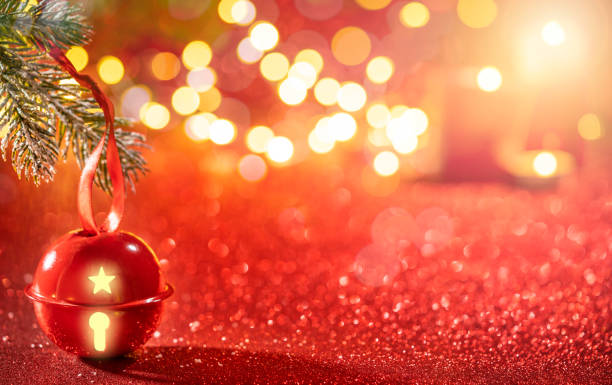 istock Red Jingle bell glowing with Christmas lights on sparkling red b 1356365097