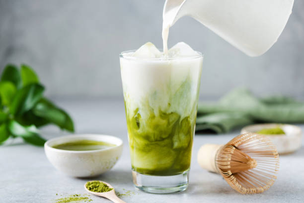 lait de soja versé dans du thé glacé matcha - thé matcha photos et images de collection