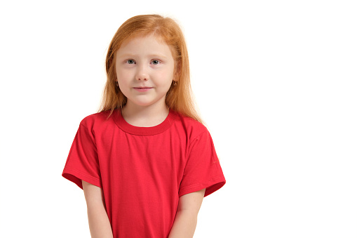 Portrait of cute redhead emotional little girl in red t-shirt isolated on a white. Beautiful studio portrait of female little caucasian person