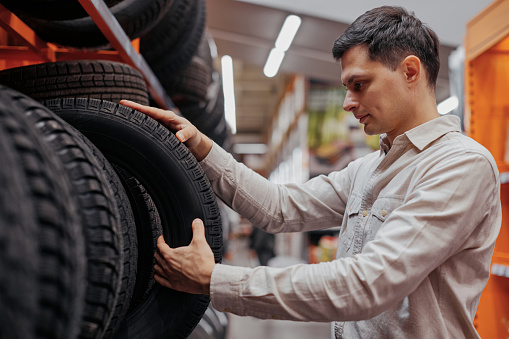 man customer choosing new tires in the supermarket. auto shop with car goods.