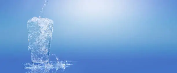 Photo of pouring water into a water glass, isolated drinking glass in front of a bright blue sunny and abstract background, close-up of a carbonated refreshing mineral water, beautiful concept with copy space