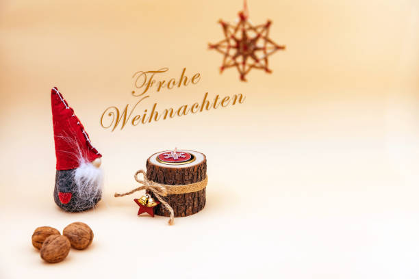Christmas postcard with text Frohe Weihnachten and a beige background, nuts, wooden candle and a funny gnome stock photo