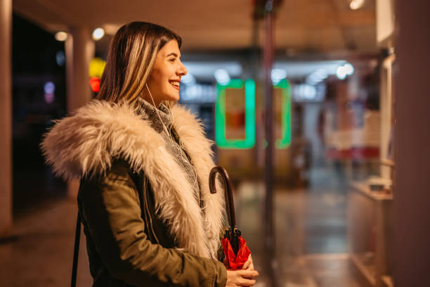 istock Smiling woman window shopping in evening 1356372057