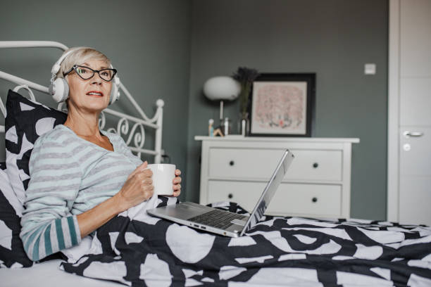 istock Senior woman lying in bed and using laptop 1356372683