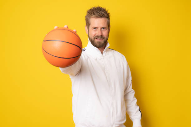 istock Young man with a basketball isolated over yellow background. 1356372718