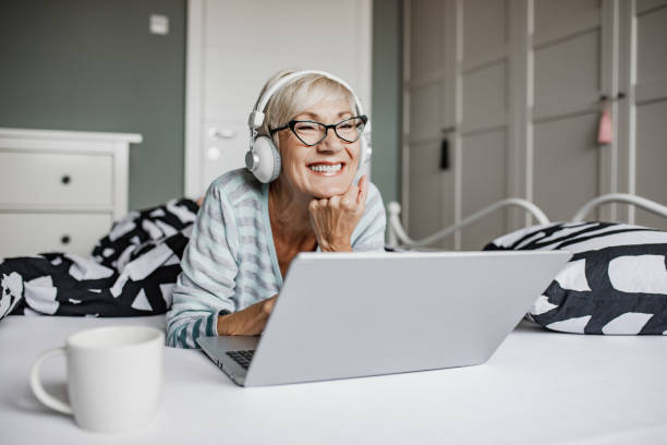 istock Senior woman lying in bed and using laptop 1356373697