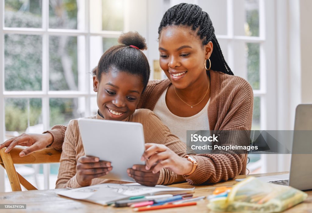 Shot of a young mother and daughter using a digital tablet at home Technology helps make homework easier Child Stock Photo
